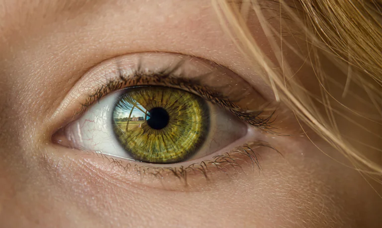 Närbild av ett mänskligt grönt öga med detaljerad iris och reflektioner.