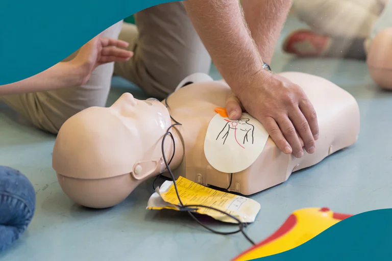 En person utför hjärt-lungräddning på en övningsdocka utrustad med en defibrillator.