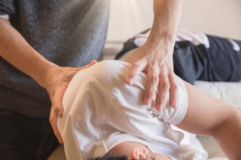 Kiropraktor som justerar en patients axel under en behandling.