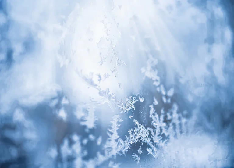 Närbild av frostmönster som bildats på ett fönster i vinterväder.