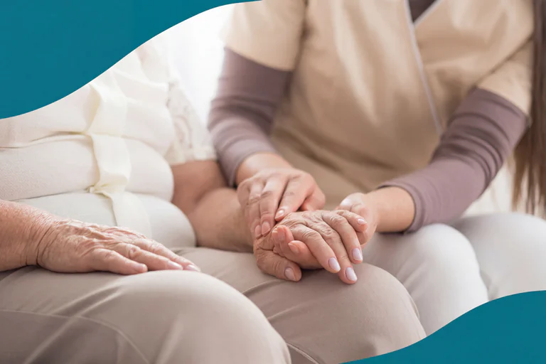 En vårdgivare håller en äldre patients hand med värme och medkänsla.