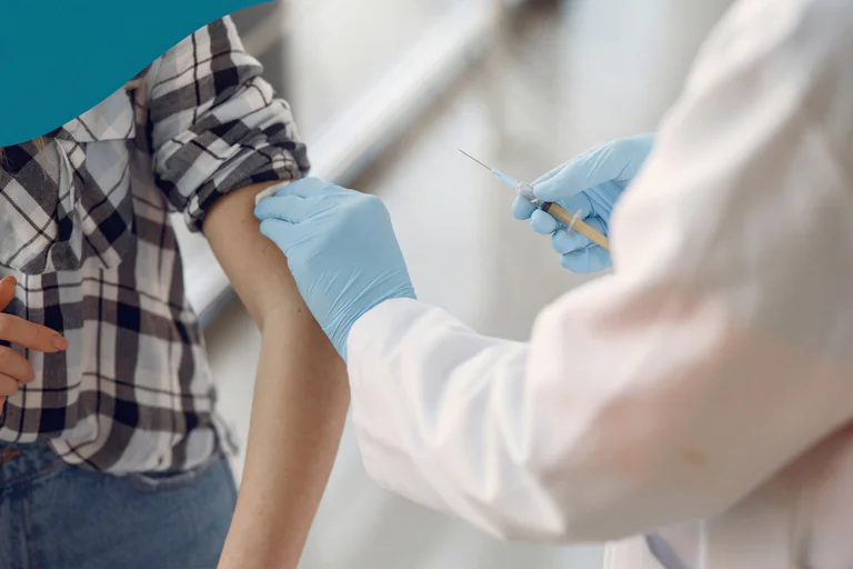 Läkare i blåa handskar ger en vaccination i armen på en patient.